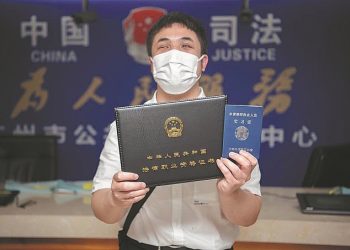 Pan Mingjing displays his legal qualification certificate at a public legal services center in Guangzhou, Guangdong province, in May. [Photo/China Daily]