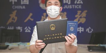 Pan Mingjing displays his legal qualification certificate at a public legal services center in Guangzhou, Guangdong province, in May. [Photo/China Daily]