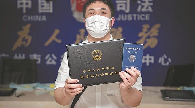 Pan Mingjing displays his legal qualification certificate at a public legal services center in Guangzhou, Guangdong province, in May. [Photo/China Daily]