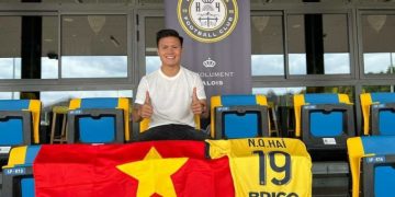 Nguyễn Quang Hải ngồi trên khán đài và khoe áo đấu số 19.