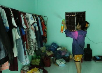 Chị Bảy dùng bình xịt vào nơi treo quần áo để diệt muỗi. Ảnh: Đình Văn