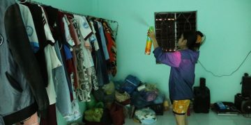 Chị Bảy dùng bình xịt vào nơi treo quần áo để diệt muỗi. Ảnh: Đình Văn