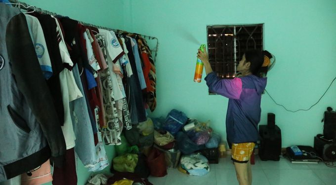 Chị Bảy dùng bình xịt vào nơi treo quần áo để diệt muỗi. Ảnh: Đình Văn